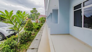 A building with a light blue exterior, a paved walkway, and a row of windows. - OYO 3277 Inayah Pkpri Hotel Syariah (Serang)