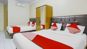 A hotel room with two beds, each with red and white bedding, a large mirror, and a wardrobe. - OYO 3277 Inayah Pkpri Hotel Syariah (Serang)