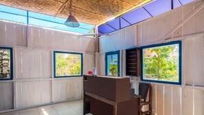 A room with a wooden desk, a chair, and large windows with blue frames. - OYO 3562 Pondok Inspirasi Minggir (Minggir)
