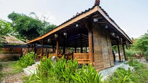 A wooden pavilion with a tiled roof, surrounded by lush greenery and steps leading up to it. - OYO 3562 Pondok Inspirasi Minggir (Minggir)