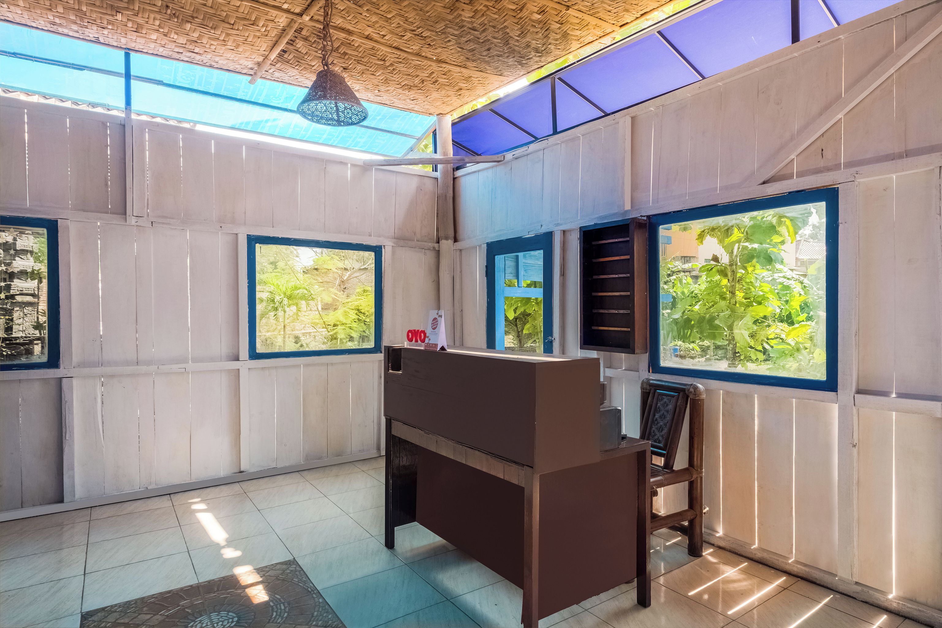 A room with a wooden desk, a chair, and large windows with blue frames.