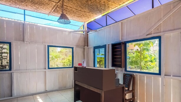 Una habitación con un escritorio de madera, una silla y ventanas grandes con marcos azules.