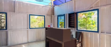 A room with a wooden desk, a chair, and large windows with blue frames.