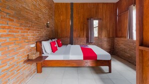 A bedroom with a wooden bed, brick walls, and a window with curtains. - OYO 3562 Pondok Inspirasi Minggir (Minggir)