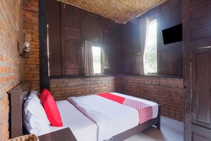Una habitación con una cama, una pared de ladrillo, techo de madera y una ventana con cortinas.
