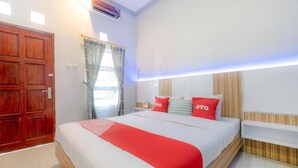 Une chambre d’hôtel avec un grand lit, une tête de lit en bois et un coussin décoratif rouge.