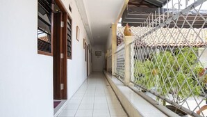 A corridor with tiled flooring, a metal fence, and a view of a tiled roof and greenery. - Spot ON 3961 Fico's Residence Syariah (Bekasi)