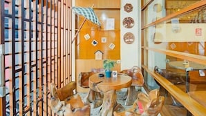 Un coin salon accueillant, avec des chaises en bois et une table ronde, entouré d’une cloison en bois dotée de lattes verticales.