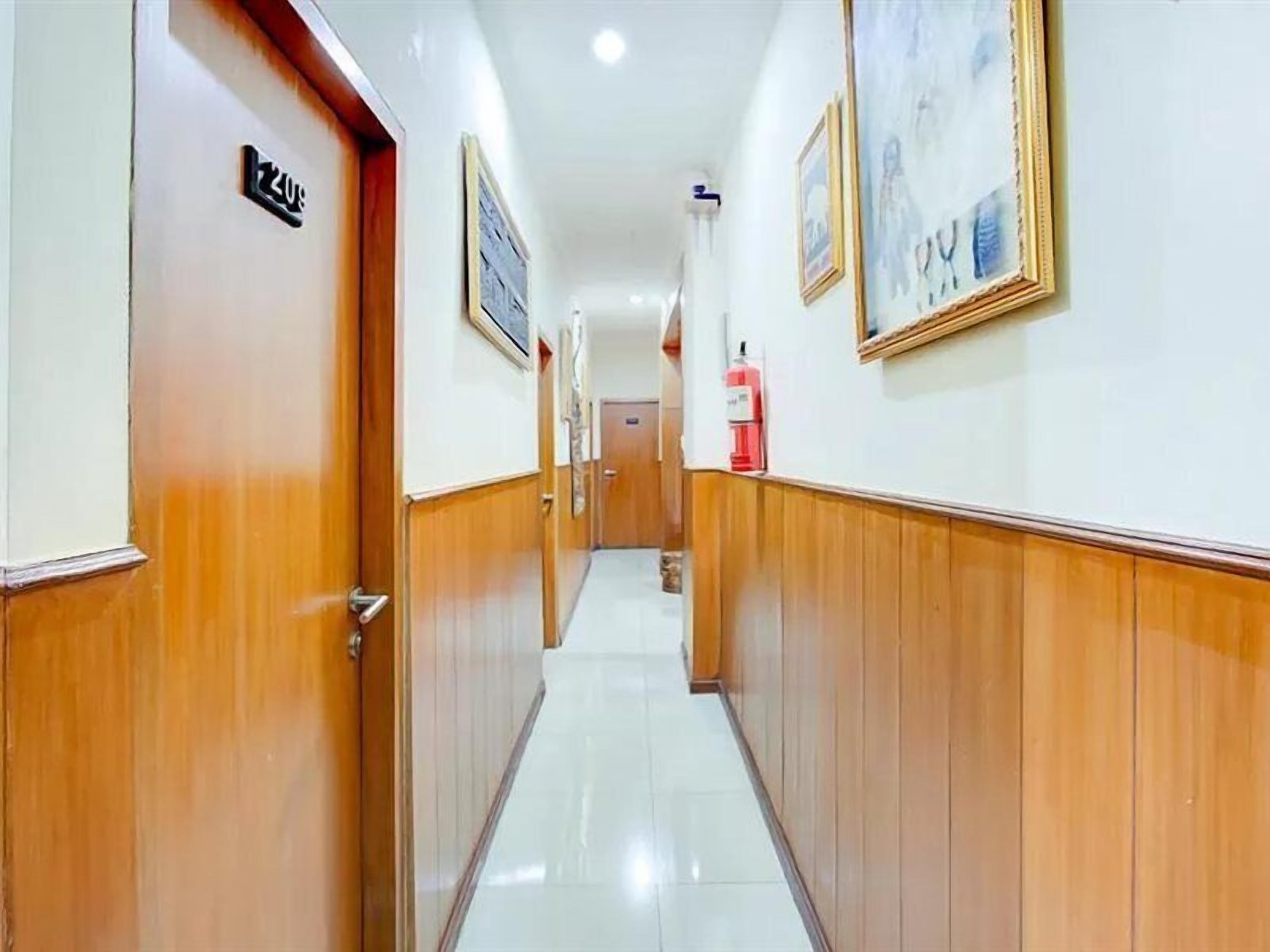 A hallway with wooden paneling, a fire extinguisher, and framed pictures on the walls.