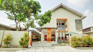 A two-story building with a modern design, featuring a central entrance with orange pillars, a balcony on the upper floor, and a sign that reads "Anugerah." - OYO 3338 Wisma Anugerah Syariah (Surakarta)