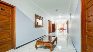 A hallway with wooden doors, a glass-top table, and a mirror on the wall. - OYO 3338 Wisma Anugerah Syariah (Surakarta)