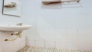 A bathroom with a white sink, a mirror, and a towel rack. - OYO 3338 Wisma Anugerah Syariah (Surakarta)