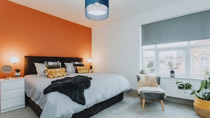 A bedroom with a bed, bedside tables, a chair, a window, and a potted plant. - Entire House with Parking in Rugby (Rugby)