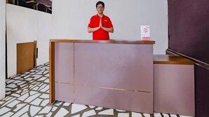 A reception desk with a person standing behind it, a patterned floor, and a plain wall in the background. - OYO 90025 Pondok Pesona Lembang (Lembang)