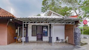 A building with a covered patio area, a small seating area with chairs, and a statue. - OYO 90025 Pondok Pesona Lembang (Lembang)