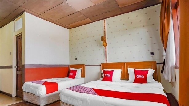 A hotel room with two beds, a wooden ceiling, and a patterned wall. - OYO 90025 Pondok Pesona Lembang (Lembang)