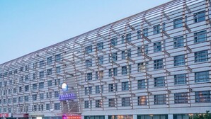 A modern building with a grid-like facade, multiple windows, and a prominent sign with text. - Tianjin Binhai Saint Light Hotel (Tianjin)