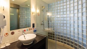 A modern bathroom with a glass shower enclosure, a white sink, and a large mirror. - Tianjin Binhai Saint Light Hotel (Tianjin)