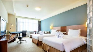 A hotel room with two beds, a desk, a chair, and a television. - Tianjin Binhai Saint Light Hotel (Tianjin)
