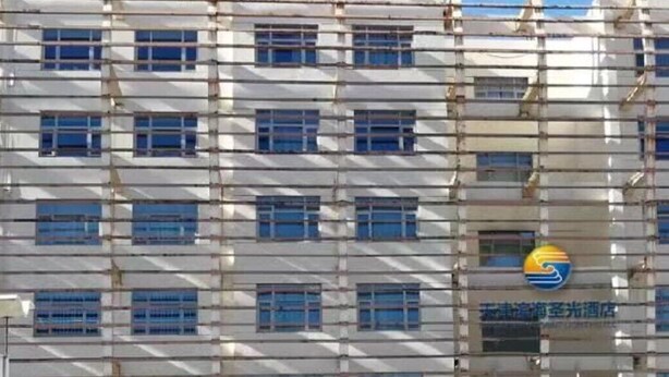 A multi-story building with a grid of windows and a logo in the center. - Tianjin Binhai Saint Light Hotel (Tianjin)