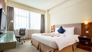 A hotel room with a bed, a desk, a chair, a TV, and a window with curtains. - Tianjin Binhai Saint Light Hotel (Tianjin)