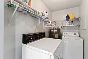 A laundry room with a Kenmore washer and dryer, a Rheem water heater, and shelves with cleaning supplies. - Beachy Isle of Palms Private Bungalow! Walk to Beach! Pet Friendly. (Isle of Palms)