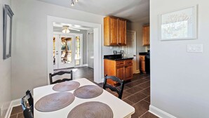 A modern kitchen with wooden cabinets, a dining area with a table and chairs, and a view of a patio with outdoor seating. - Beachy Isle of Palms Private Bungalow! Walk to Beach! Pet Friendly. (Isle of Palms)