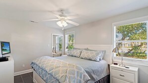 A bedroom with a bed, a nightstand, a desk, a ceiling fan, and a window with blinds. - Beachy Isle of Palms Private Bungalow! Walk to Beach! Pet Friendly. (Isle of Palms)