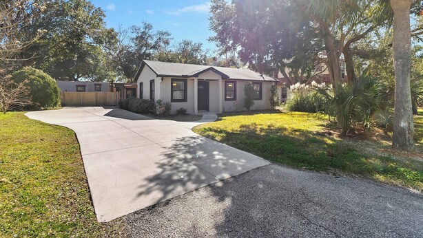 A single-story house with a front entrance, a driveway leading to the garage, and a well-maintained lawn. - Beachy Isle of Palms Private Bungalow! Walk to Beach! Pet Friendly. (Isle of Palms)
