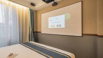 Een hotelkamer met een bed, een scherm waarop een bericht wordt geprojecteerd, en een raam met gordijnen.