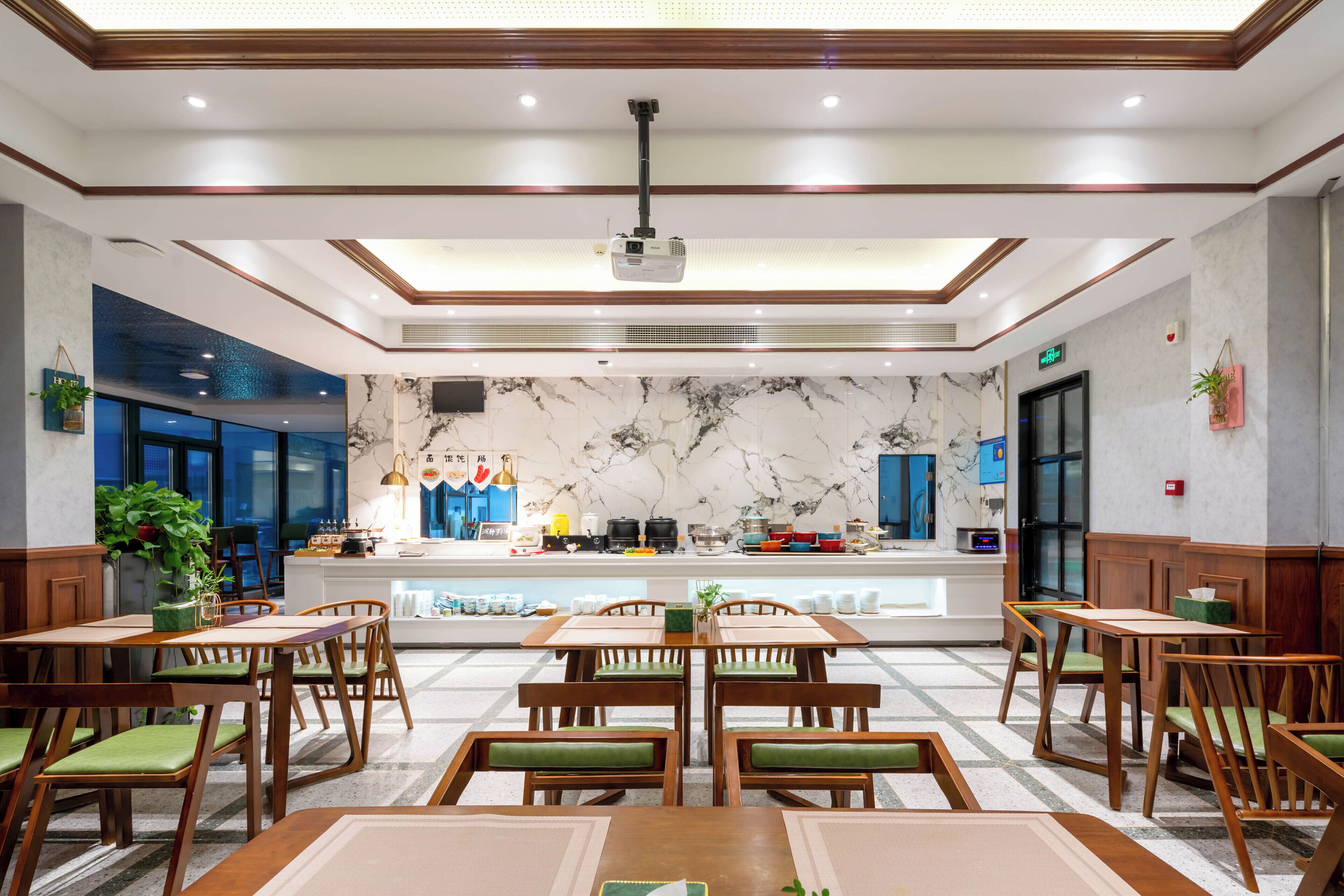 Un restaurant moderne avec des tables et des chaises en bois, un pare-feu en marbre et un projecteur fixé au plafond.