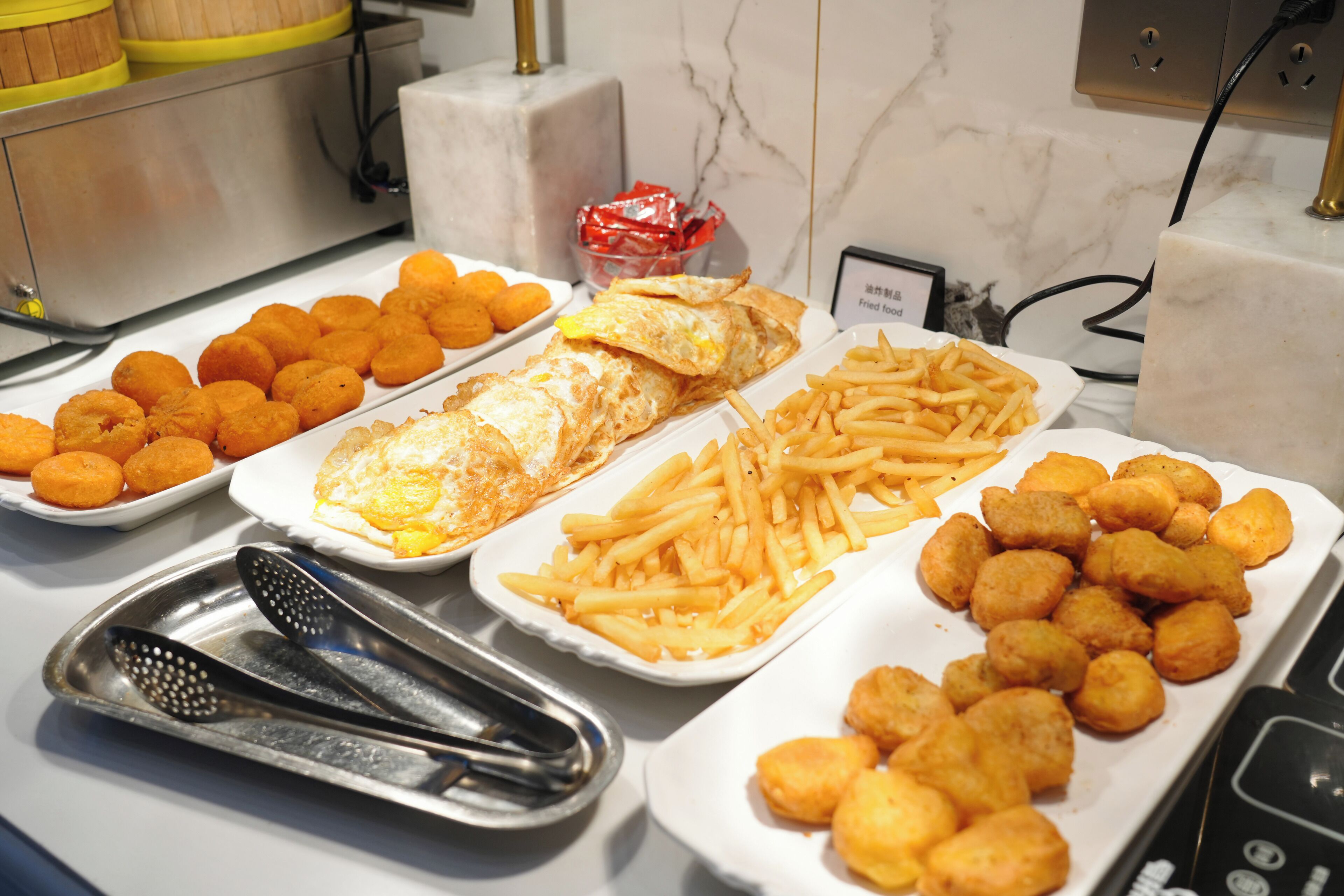 A buffet with various food items including tater tots, French fries, and fried eggs.