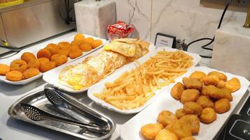 A buffet with various food items including tater tots, French fries, and fried eggs.