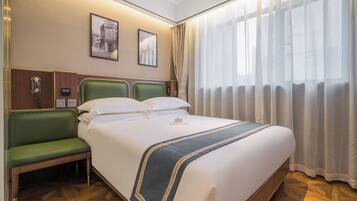 Habitación de hotel con una cama grande, un banco verde, un teléfono y dos cuadros en la pared.