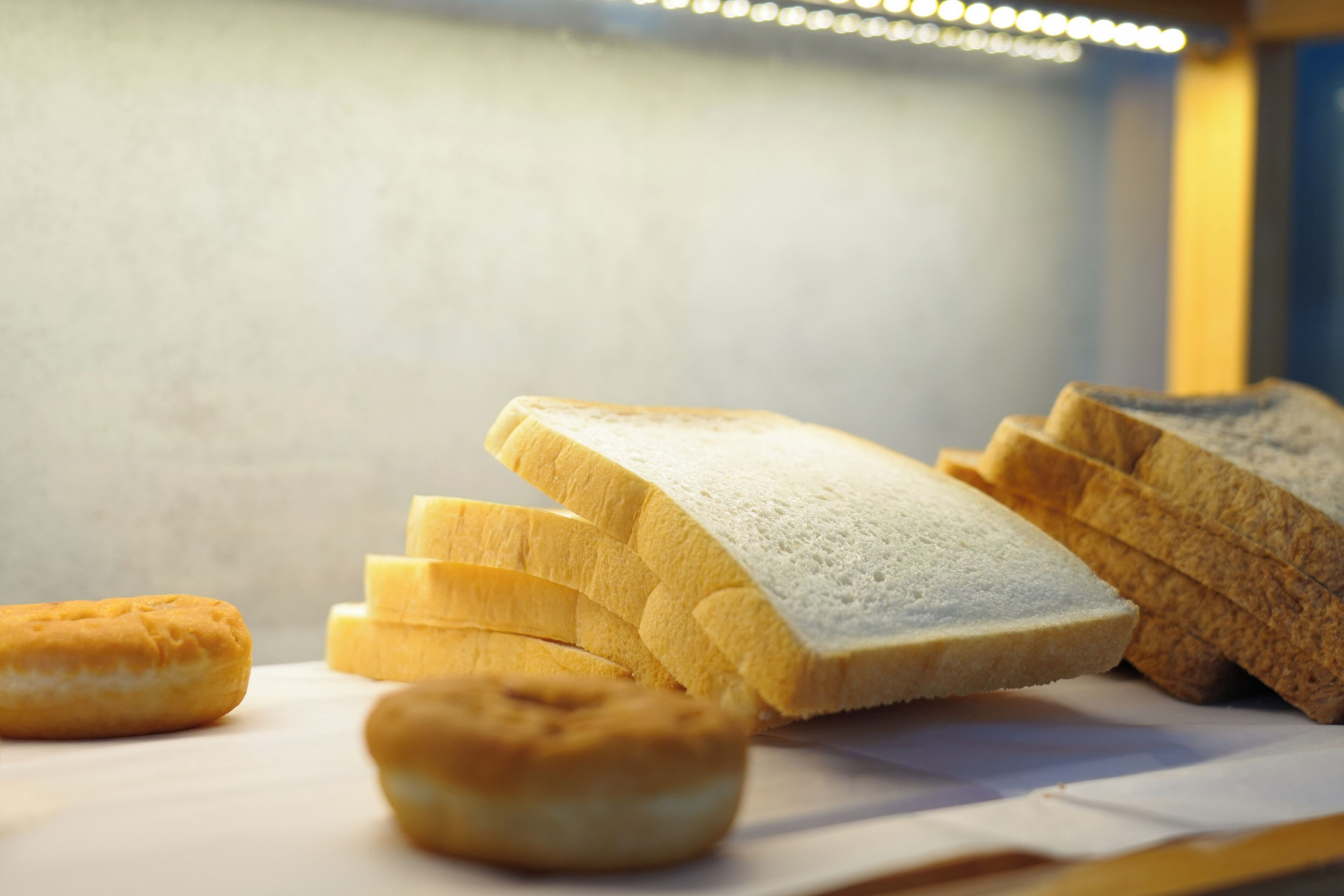 Slices of white bread and a round pastry on a white surface.