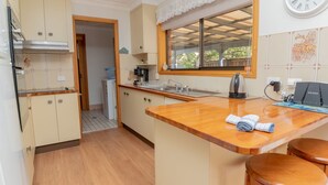 A compact kitchen with wooden countertops, a built-in stove, and a window overlooking a balcony.