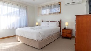 A neatly arranged bedroom with a large bed, two bedside tables with lamps, and a wooden wardrobe.