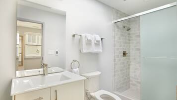Un bagno moderno con cabina doccia in vetro, lavandino bianco e water.
