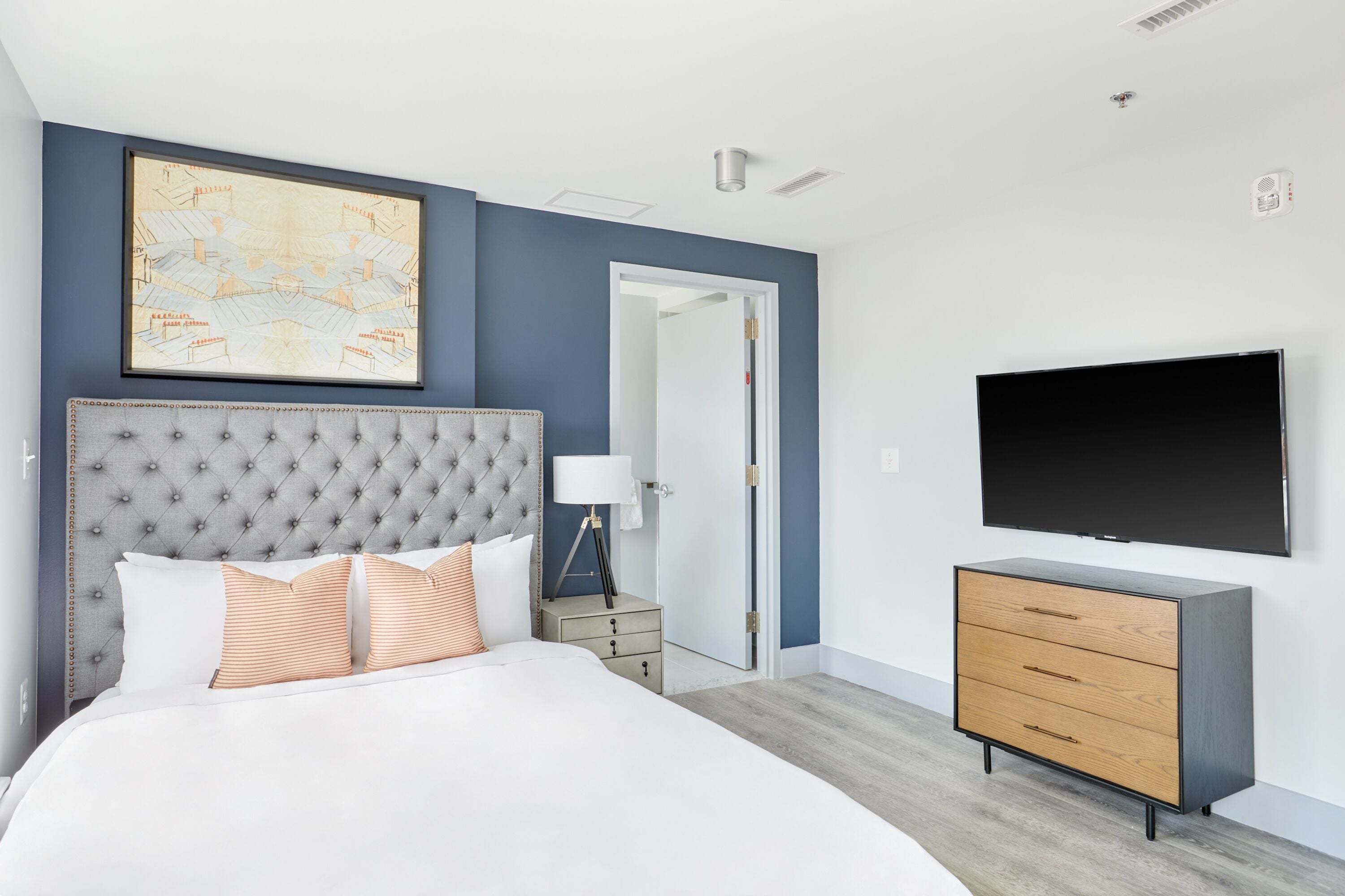 Un dormitorio con una cama grande, un aparador, un televisor y una puerta que da a otra habitaci ón.