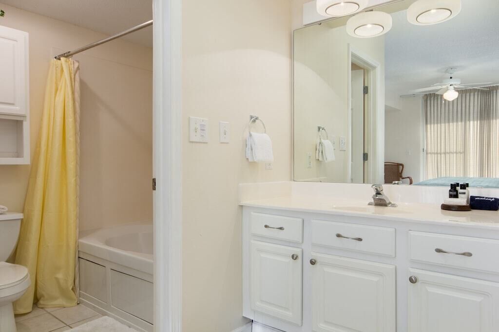 A bathroom with a bathtub, a toilet, a sink with a mirror, and a shower curtain.