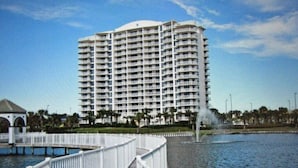 A high-rise hotel with multiple balconies, a waterfront view, and a fountain.