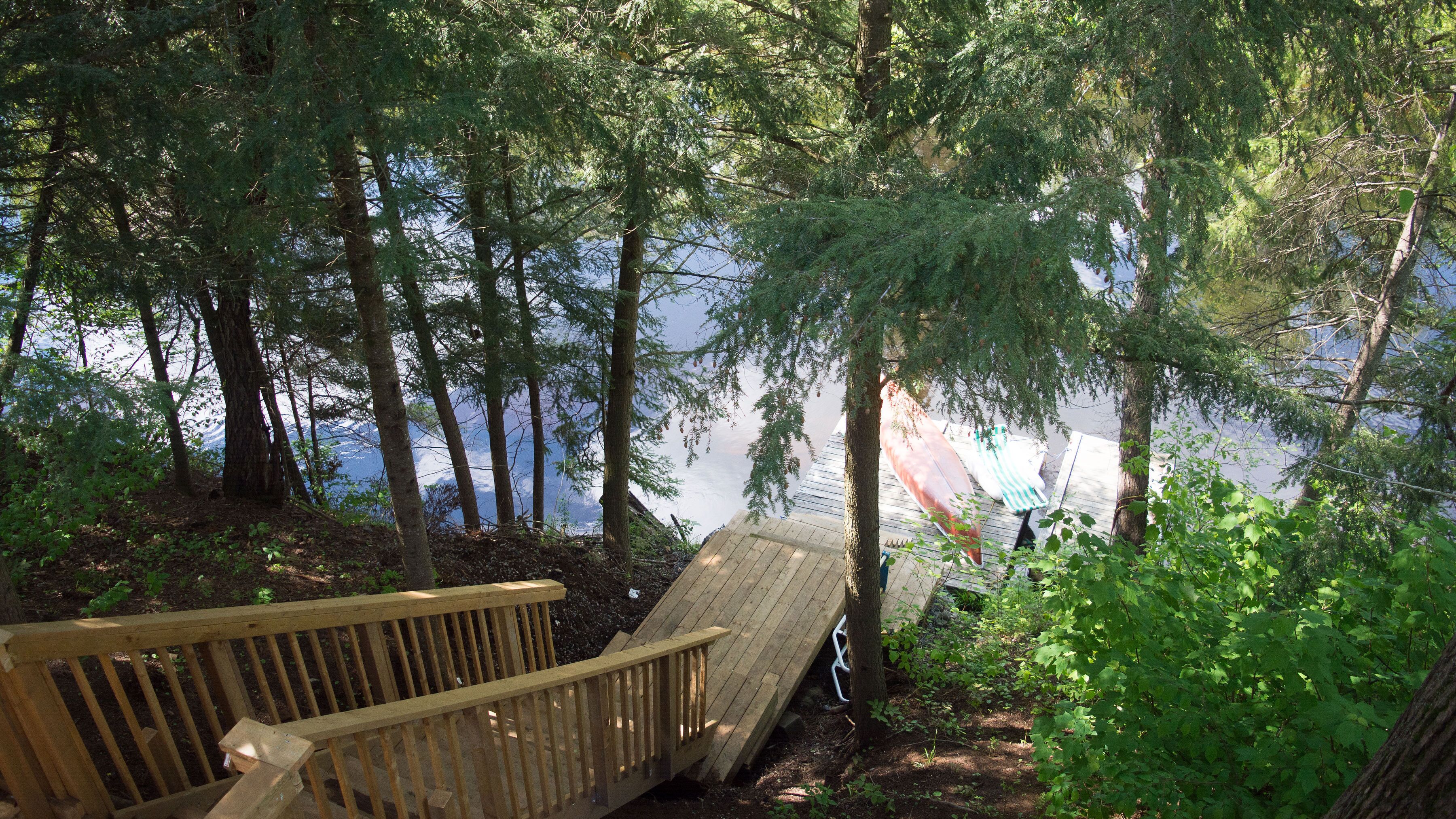 Una terraza de madera con vistas a un lago y un bosque.