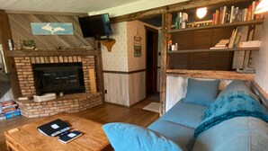 A cozy living room with a brick fireplace, a wooden coffee table, a blue sofa, and a bookshelf filled with books. - House in Bessemer - 3 BR/1.5 Bathrooms (Bessemer)