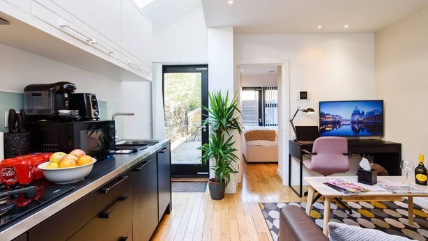 Una cocina moderna con comedor, una sala de estar con televisor y un balcón con vistas.
