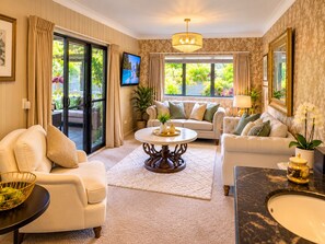 A spacious living room with a sofa, armchairs, a coffee table, and a TV.