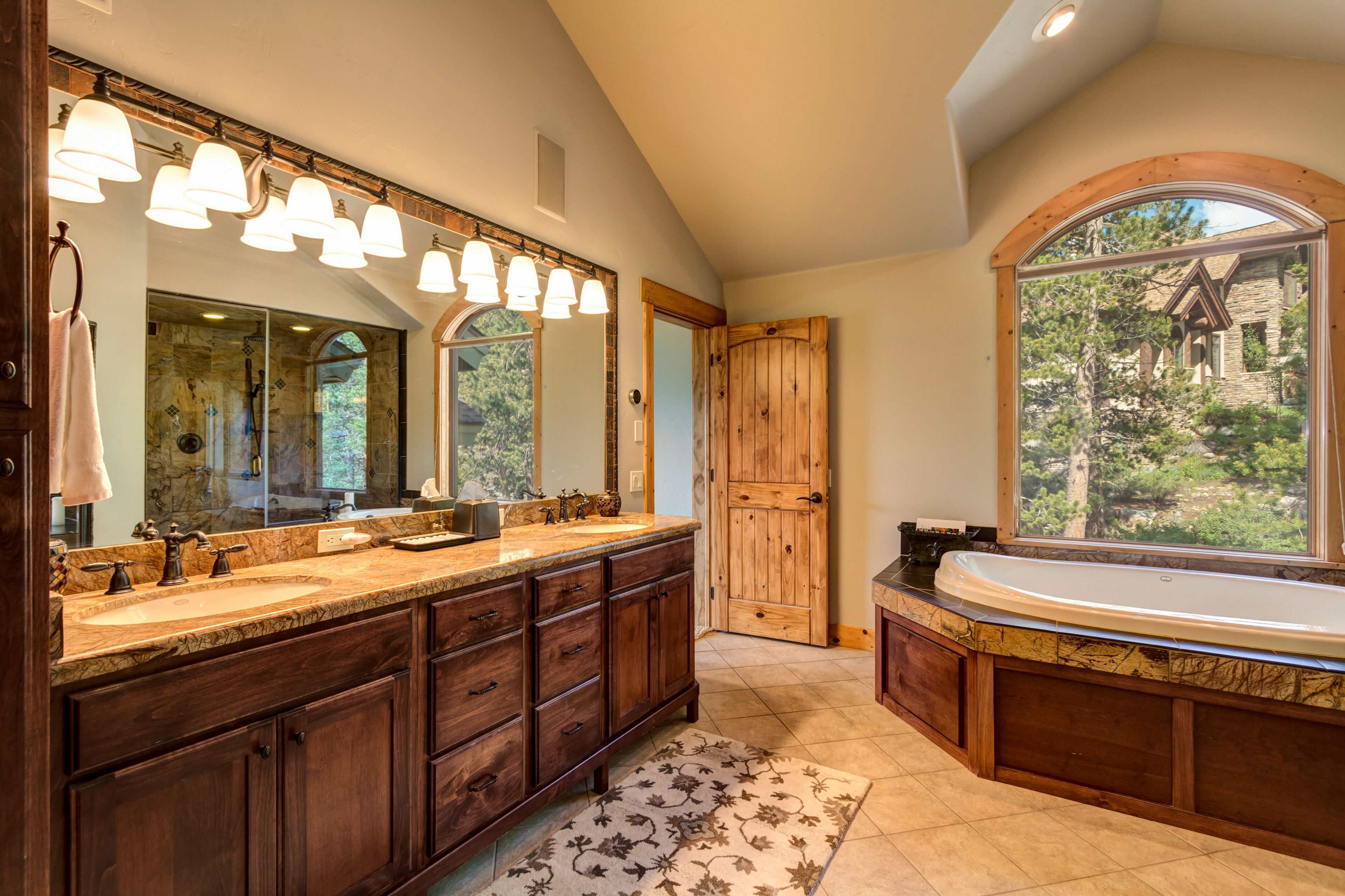 A bathroom with a double sink vanity, a large mirror, and a freestanding bathtub.