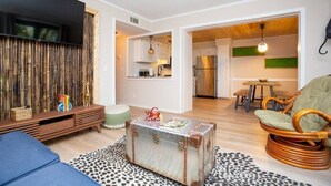 A modern living room with a sofa, a vintage suitcase, and a dining area with a table and chairs.