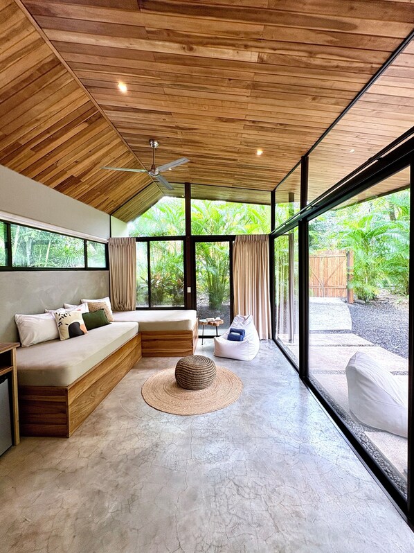 A modern interior with a wooden ceiling, large windows, a sofa, a bean bag, and a round woven rug. - Villa Kawai at Villas Kalei Private Boutique Hotel in Playa Grande Guanacaste CR (Playa Grande)