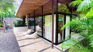 Una casa moderna con techo de madera, amplios ventanales y un camino de grava que conduce a una zona de estar.