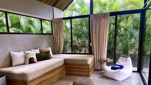 Un espacio habitable moderno y de planta abierta con sofá integrado, un sillón de saco y un pouf tejido.